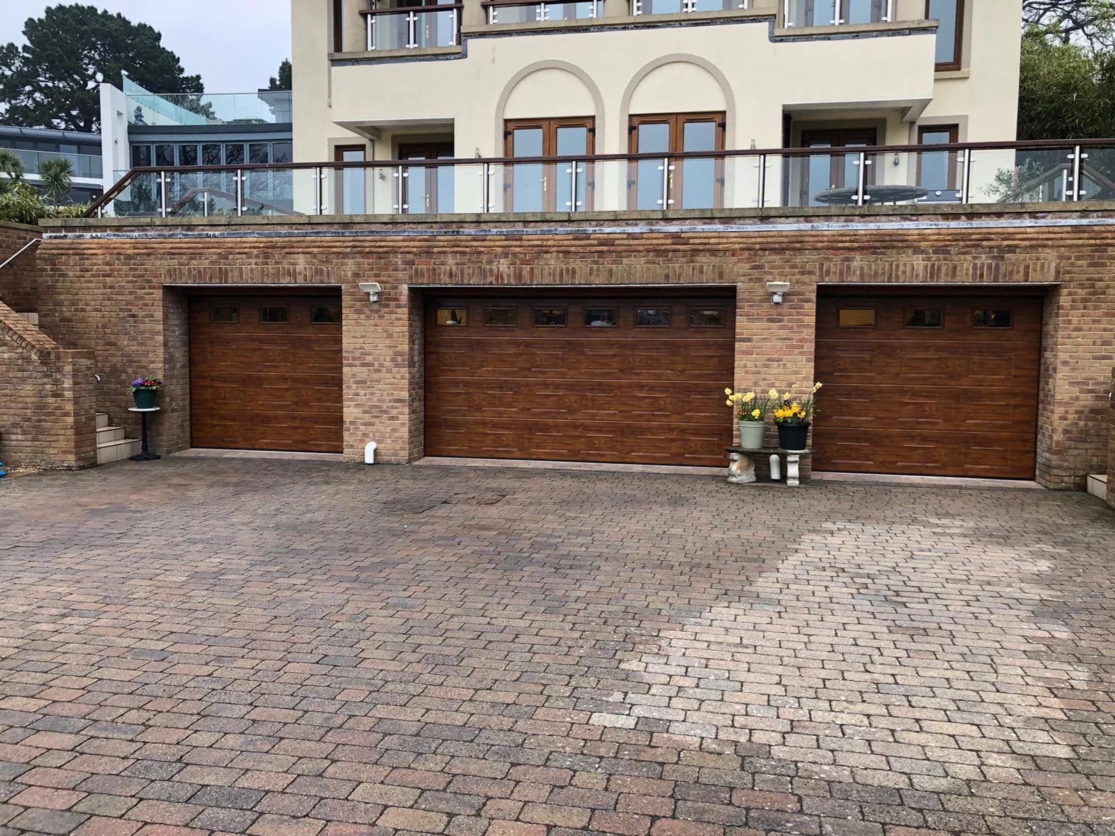 Dark oak triple garage doors installed on brick property