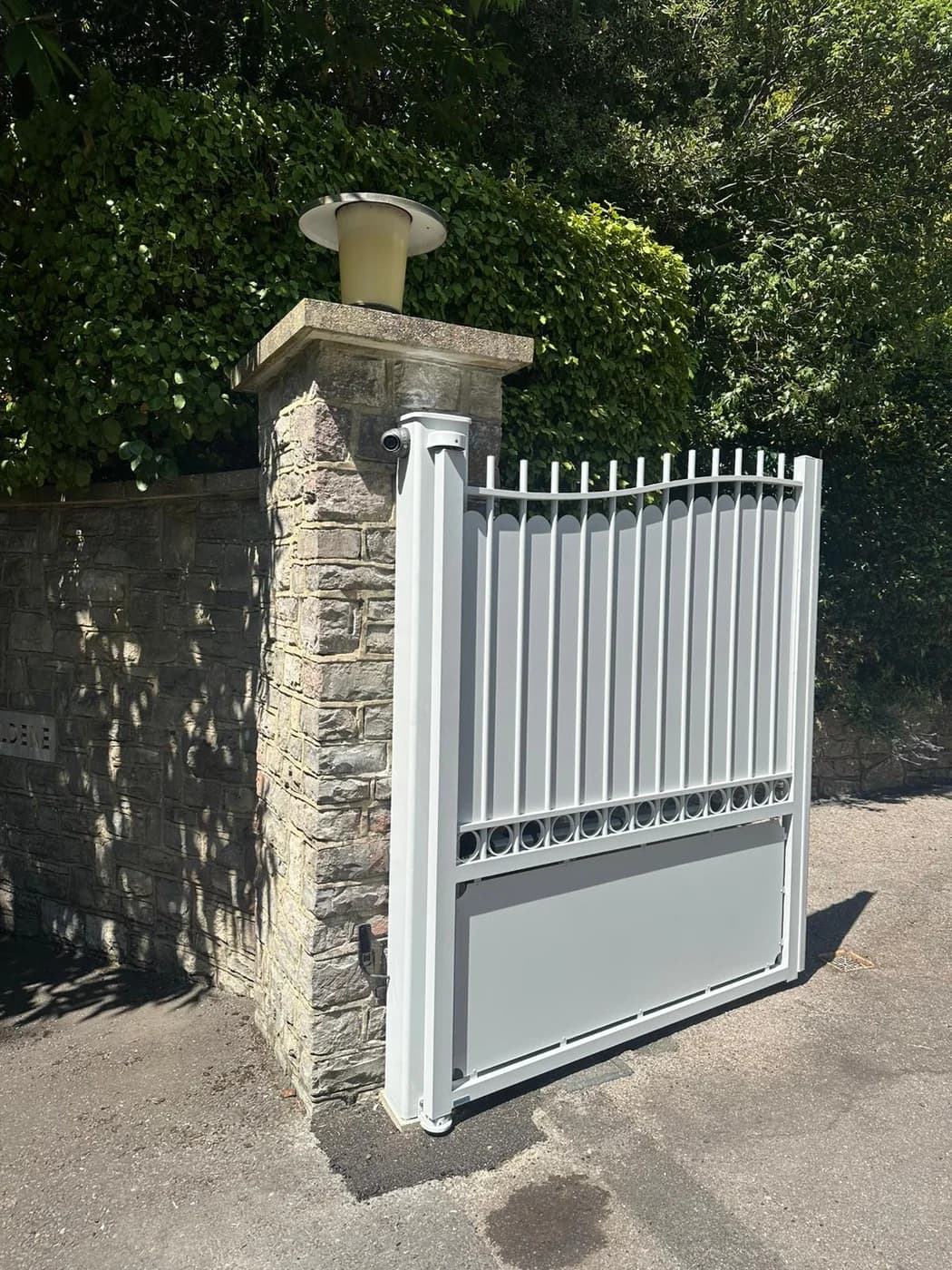 Automated white gate close up with stone entrance pillars
